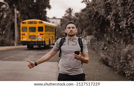 The young man missed the bus, a male backpacker hitchhiking, a hitchhiker with thumb up catching a car.