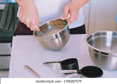 Young Man Mixing Batter For Pancakes In A Bowl