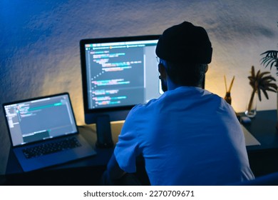 Young man mobile developer writes program code on a computer, programmer work in home office.
