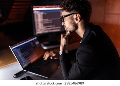 Young man mobile developer writes program code on a computer, programmer work in home office.