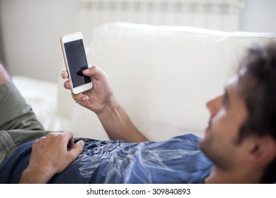 Young Man With Mobile Phone On The Sofa