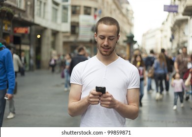 Young Man With Mobile Phone Walking, Background Is Blured City