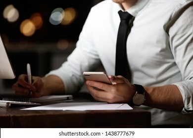 Young man with mobile phone working in office at night, closeup - Shutterstock ID 1438777679