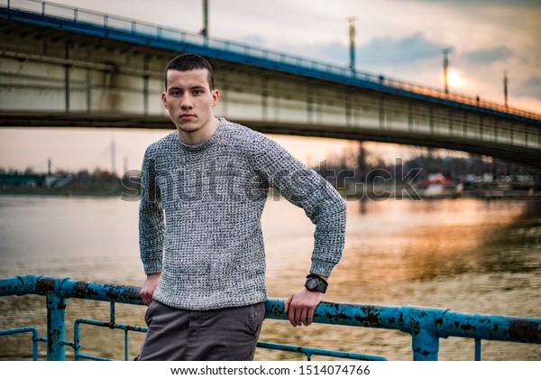 ブランコの橋 サヴァ川 夕日を背景に フェンスに寄りかかりながらポーズをとるセーターの青年モデル の写真素材 今すぐ編集