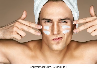 Young man with moisturizer cream on the face. Photo of man with perfect skin. Beauty & Skin care concept