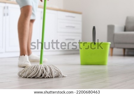 Young man mopping floor in modern kitchen, closeup Imagine de stoc © 