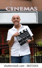 A Young Man Or Movie Critic Holding A Movie Directors Clap Board In Front Of The Cinemas.