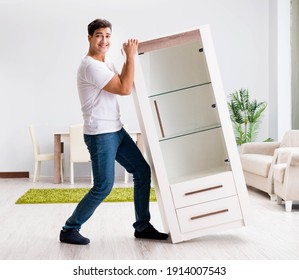 Young Man Moving Furniture At Home