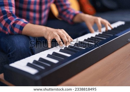 Young man musician playing piano keyboard at music studio
