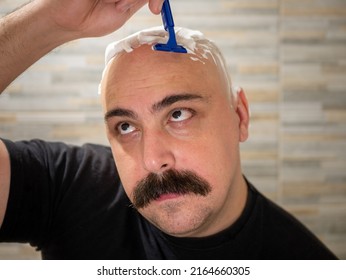 A Young Man With Mustache Shaves His Head Thoughtfully