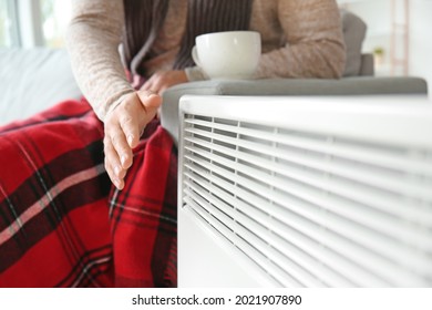 Young Man Near Electric Heater At Home. Concept Of Heating Season