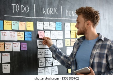 Young man near scrum task board in office - Shutterstock ID 1336305902