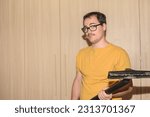 Young man with nerdy glasses and yellow t-shirt using vacuum cleaner