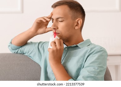 Young Man With Nosebleed And Tissue At Home