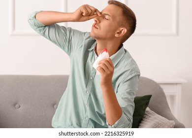 Young Man With Nosebleed And Tissue At Home