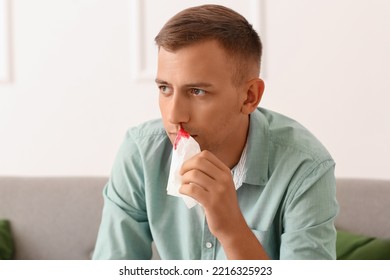 Young Man With Nosebleed And Tissue At Home, Closeup