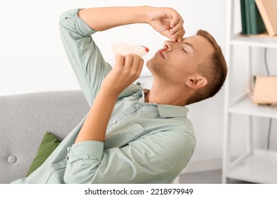 Young Man With Nosebleed And Tissue At Home