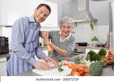 Young Man And Older Woman Cooking Together In The Kitchen.