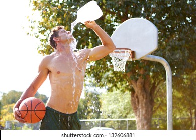 Young Man On Basketball Court Hydrating Himself With A Gallon Of Water.