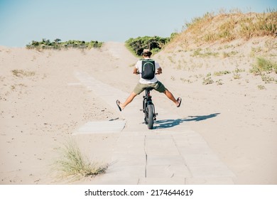 Young Man On Bicycle Having Fun With Electric Bike - Carefree Boy Having Fun And Smiling On Bicycle On The Beach On A Sunny Day - Freedom Concept