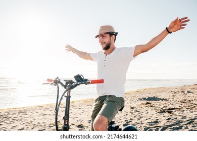 Young Man On Bicycle Having Fun With Electric Bike - Carefree Boy Having Fun And Smiling On Bicycle On The Beach On A Sunny Day - Freedom Concept