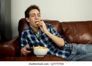 Young Man On Couch Eating Potato Chips