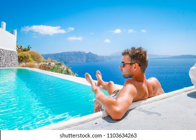 Young Man On Luxury Vacation In The Infinity Swimming Pool, Man At Swim Pool Santorni Greece