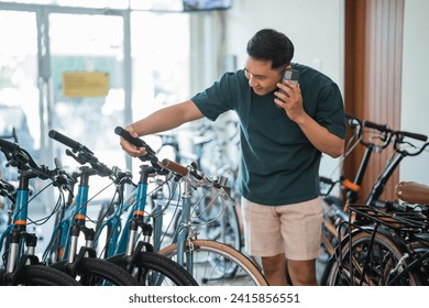 young man on phone while checking hangrip standing in bike shop - Powered by Shutterstock