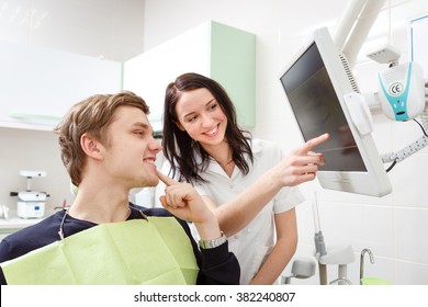 Young Man On A Review Of A Dentist, Sitting In A Chair. Dentist Explaining X-Ray On Computer For Patient In A Dental Clinic