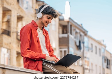 young man on the street with headphones and laptop outdoors - Powered by Shutterstock