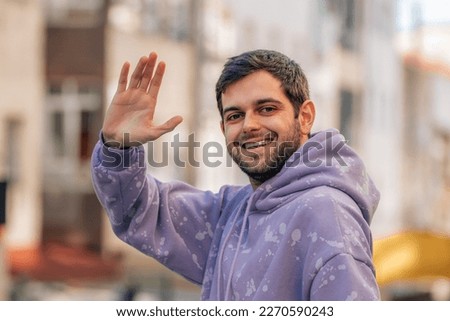 young man on the street waving