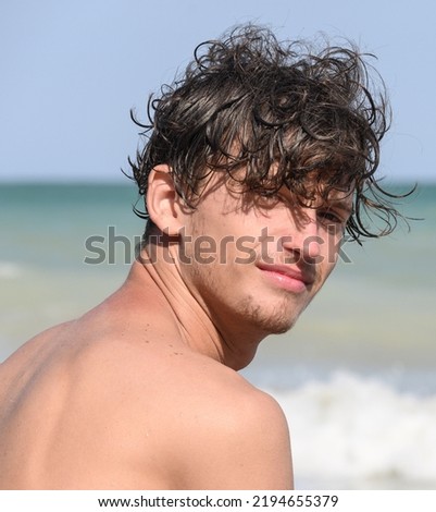 Young man on vacation, by the sea. Portrait of a young man with messy hair- Surfer hair- on the seashore. 