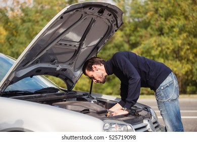 The young man opened the hood of his car and looking for a malfunction 