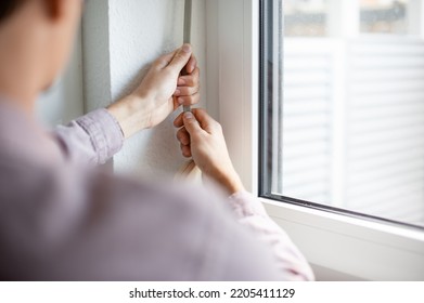 Young Man Opening Blind At Home