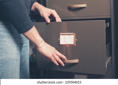 A Young Man Is Opening A File Cabinet