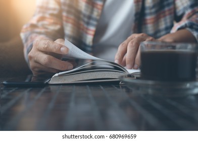 Young Man Opening And Reading A Book With A Cup Of Coffee On Table, Close Up, Vintage Style