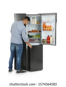 Young Man Opening Refrigerator On White Background