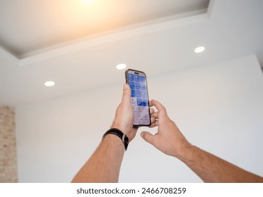 Young man operates wireless lightning system in a modern apartment.