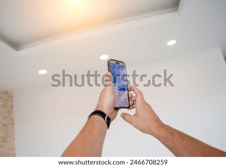 Young man operates wireless lightning system in a modern apartment.