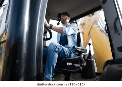 Young man operating a backhoe loader in the countryside