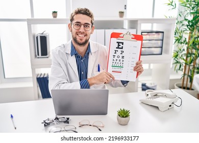 Young Man Optician Holding Snellen Test At Clinic