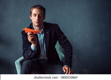 Young Man And Orange Paper Planes. Entrepreneur Or Investor, Development Planning And Financial Strategies