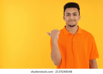 Young man in orange polo on yellow background - Powered by Shutterstock