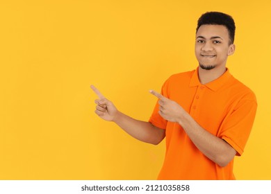 Young man in orange polo on yellow background - Powered by Shutterstock