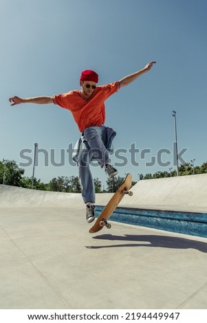young man with outstretched hands jumping on skateboard in skate park