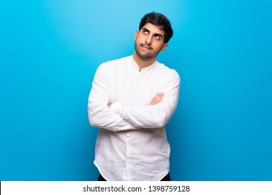 Young Man Over Isolated Blue Wall With Confuse Face Expression While Bites Lip