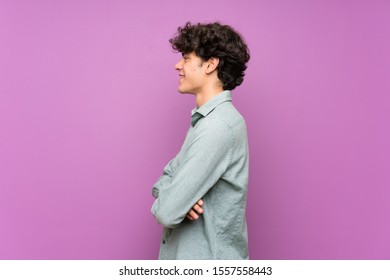 Young Man Over Isolated Purple Wall In Lateral Position