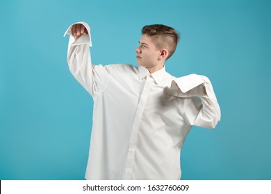 A Young Man In An Oversized White Shirt Shows That His Shirt Is Too Big For Him. Blue Background