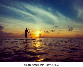Young man paddle boarding during a beautiful sunrise in Mexico  
