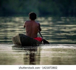 Young Man Paddling Away At End Of Day In Amazonia